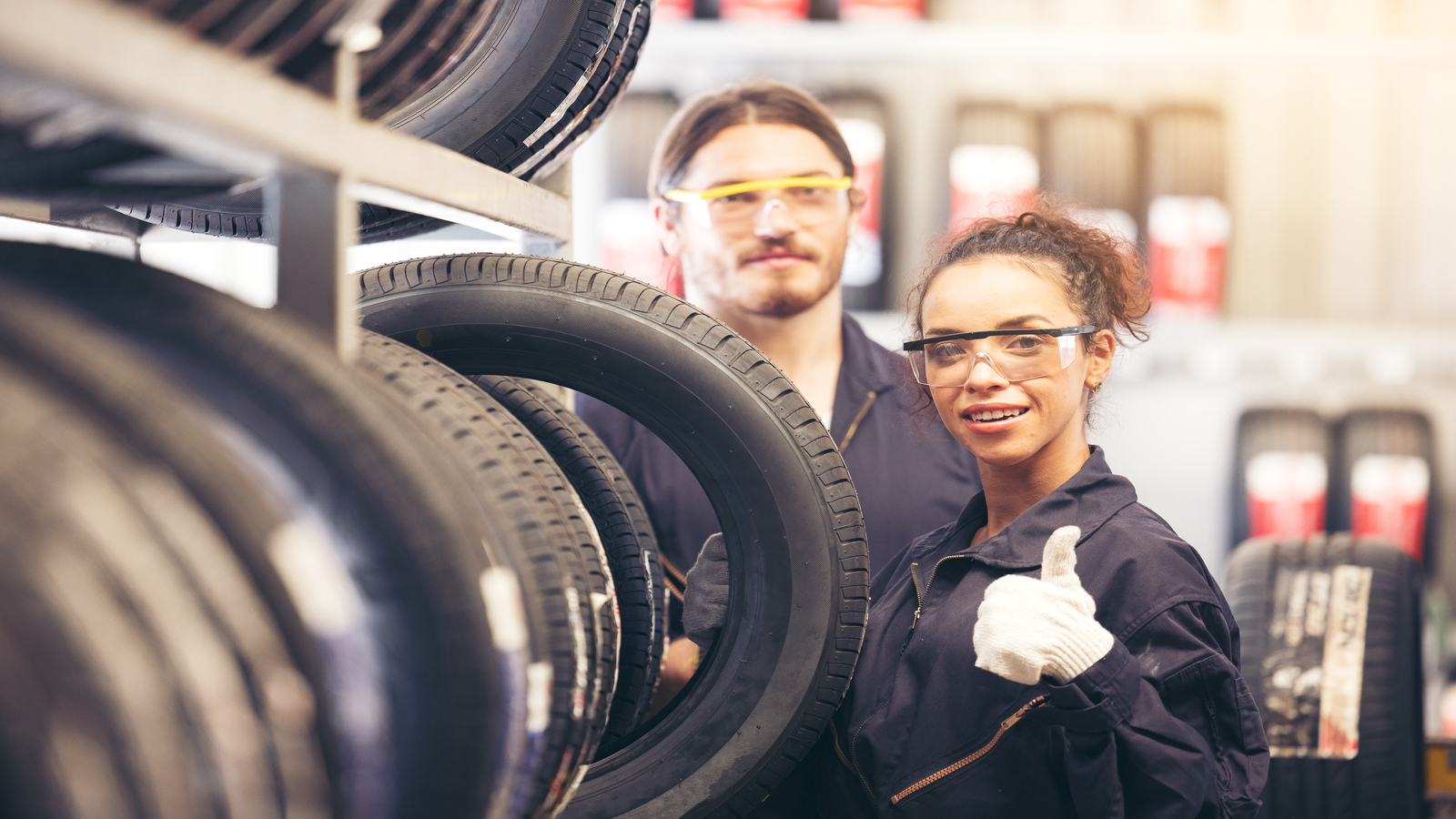 Jogo de Pneus em preteleira e dois trabalhadores ao lado um deles sinalizando aprovação